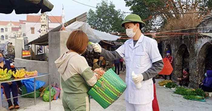 Lực lượng chức năng huyện Thanh Hà (Hải Dương) kiểm tra thân nhiệt người dân tại chợ.