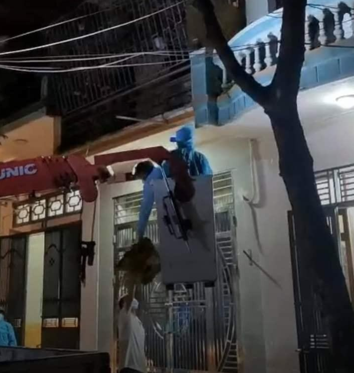 Người và máy cẩu lên tầng 3 để đưa f1 cố thủ trong nhà đi cách ly (ảnh facebook).